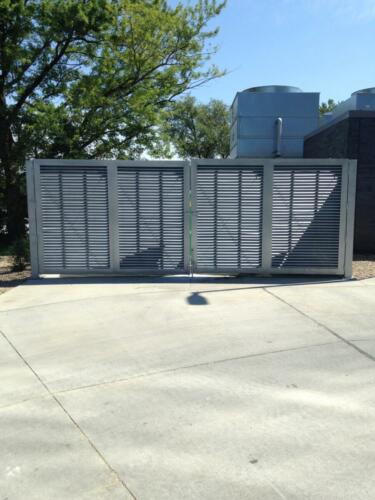 6-8 foot grey louvers on cement creating an enclosure with swing gates
