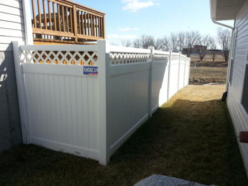 6-8 foot tall white vinyl privacy fence with a crisscross stitched pattern on the top before connecting to a straight white horizontal board that connects that a fence posts 