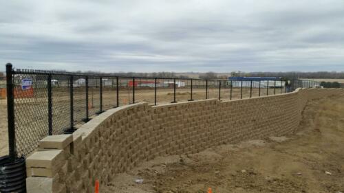 4' black vinyl chain link fence atop a large retaining wall. 