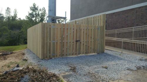 6 - 8 foot 6 - 8 foot tall wood fencing with one swing gates atop a grass surface creating an enclosure